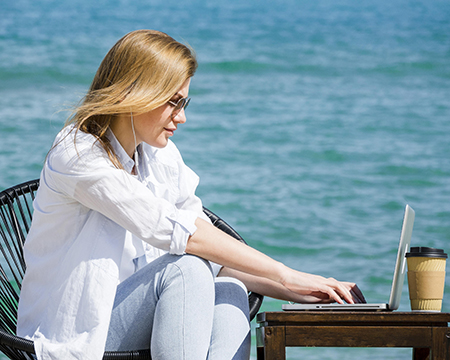 Woman working on laptop at the beach